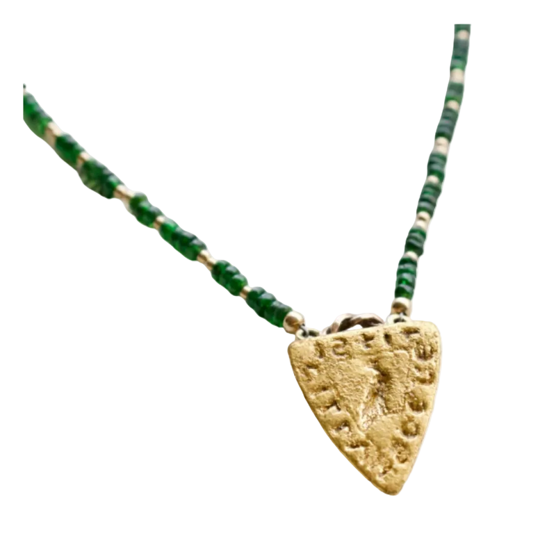 Necklace with green beads and a gold pendant on a white background